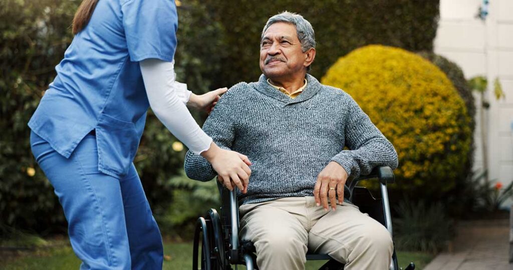 Older adult in assisted living sharing family photos with a visitor in a bright sitting room.